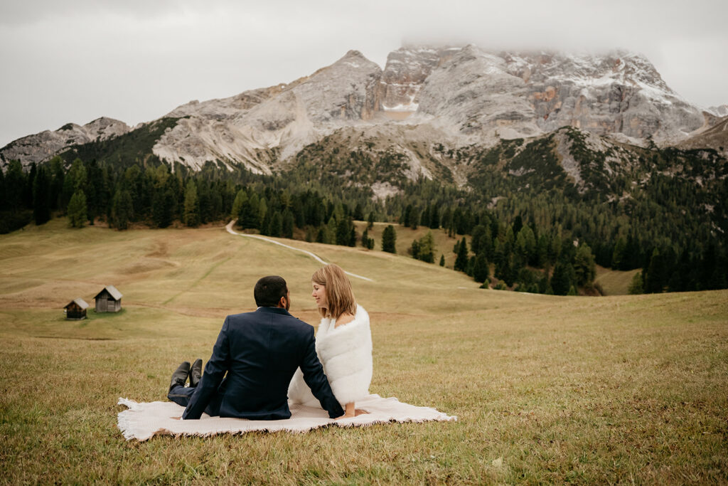 Couple sitting in mountain landscape with blanket.