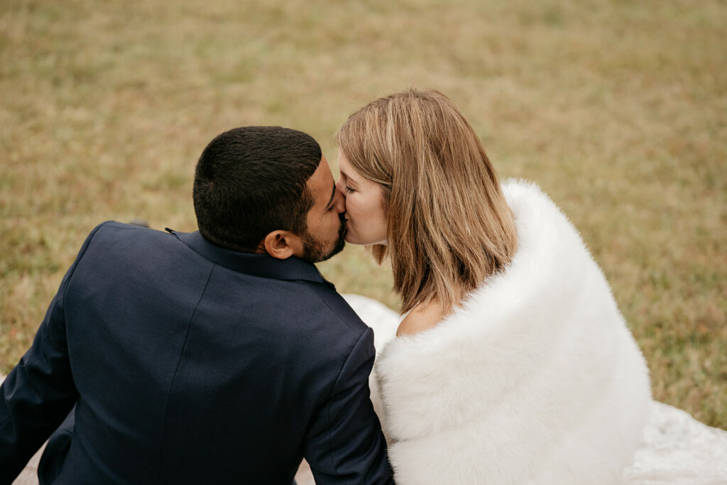 Couple kissing on grass in formal attire.