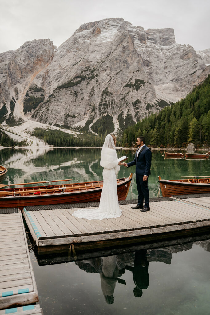Wedding couple on dock with mountain backdrop.