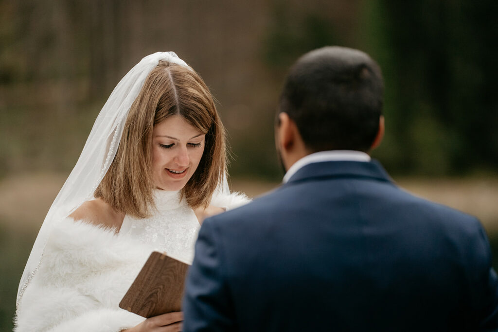 Bride reading vows during wedding ceremony outdoors.