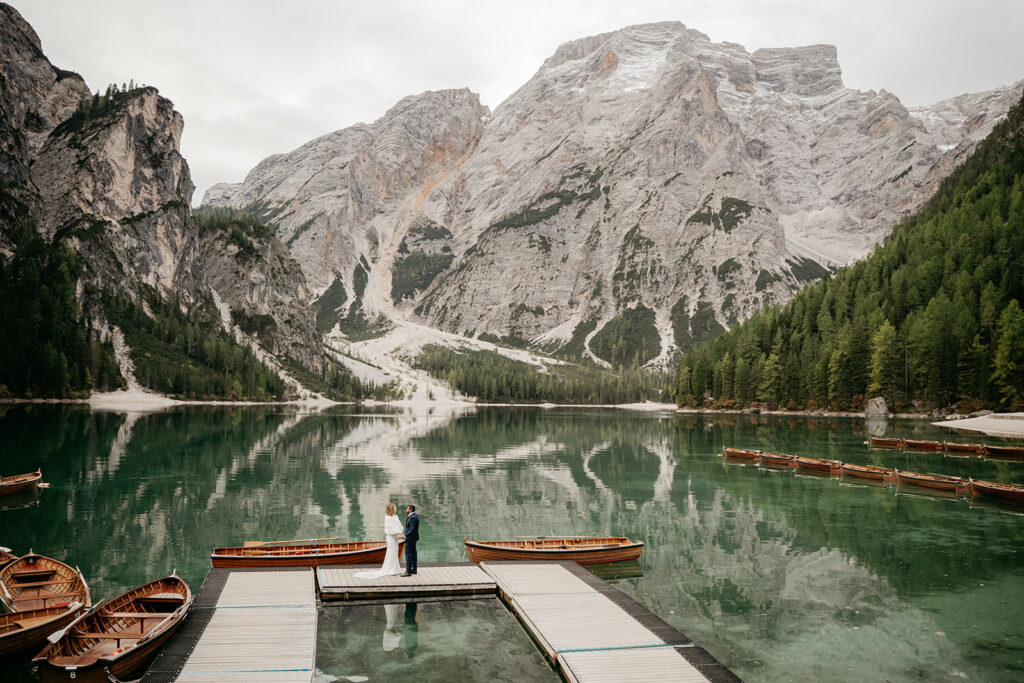 Couple on dock at mountain lake with boats.