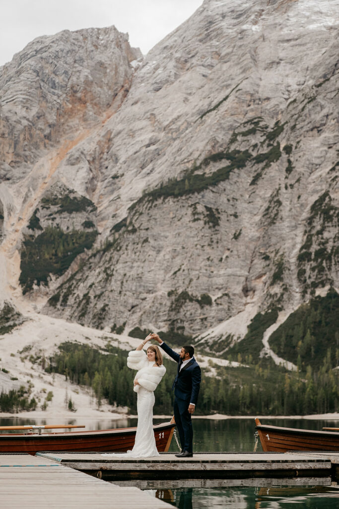 Couple dancing on dock by mountain lake.
