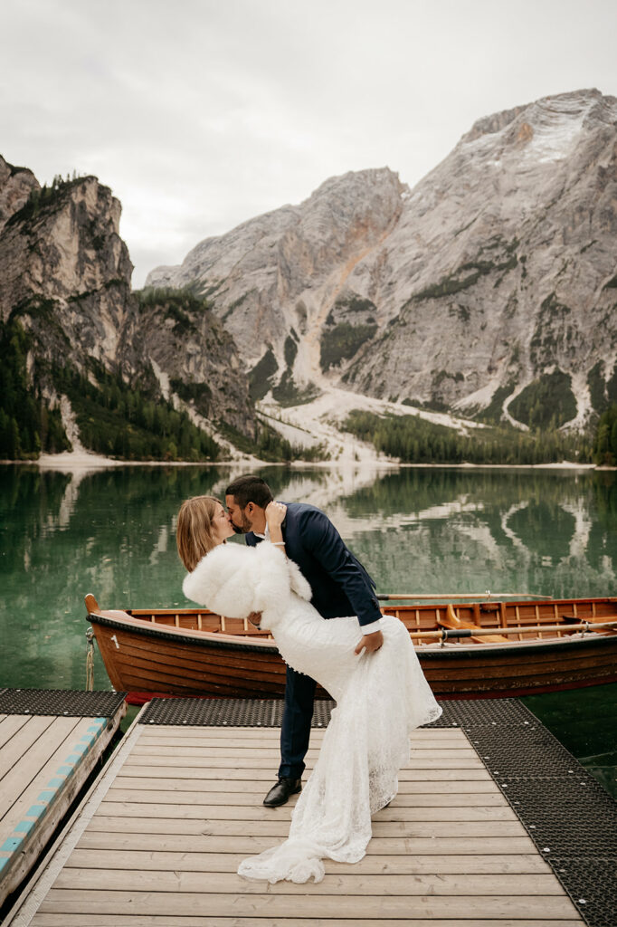 Couple kissing on dock in mountain setting.