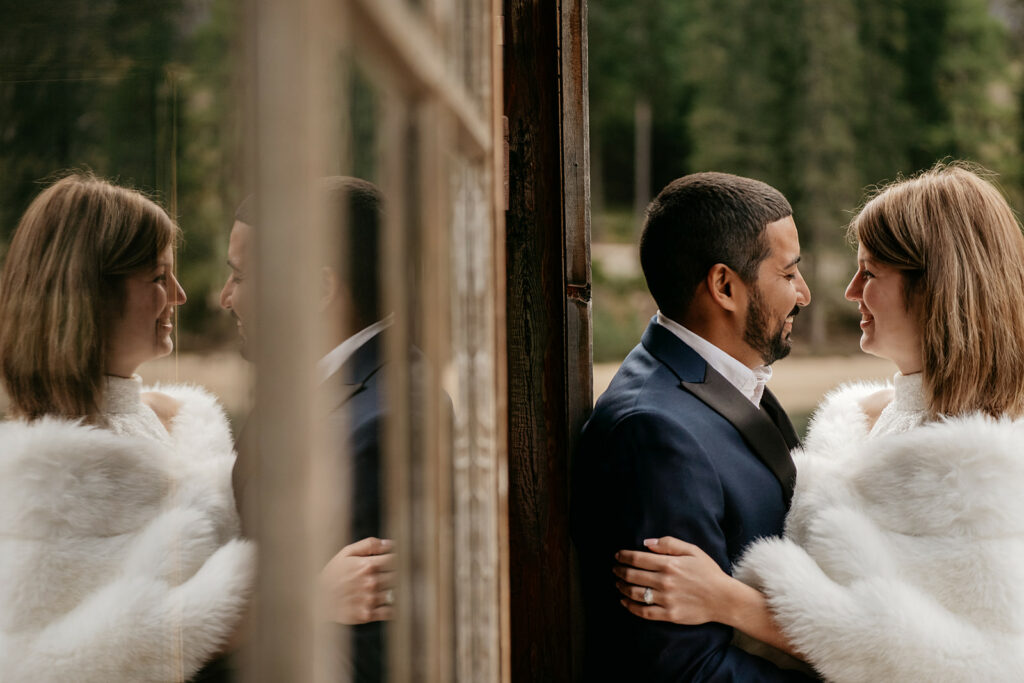 Couple embracing, dressed in formal attire, reflected in mirror.