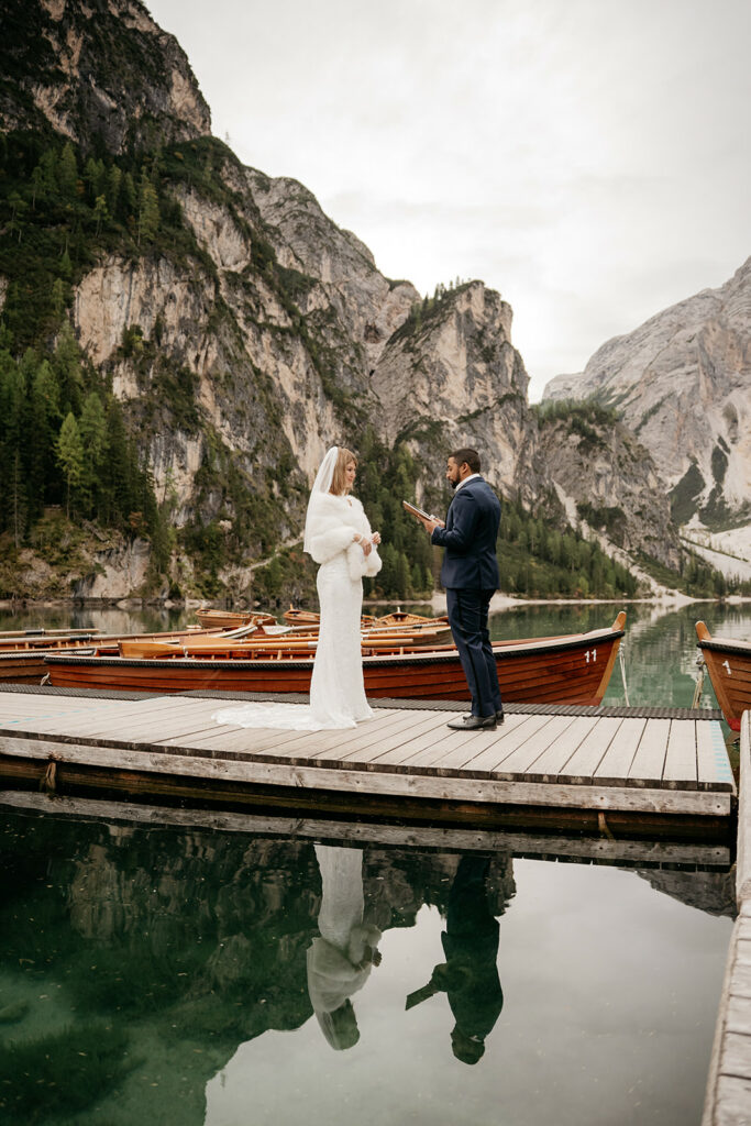 Couple exchanging vows on lakeside wooden dock.