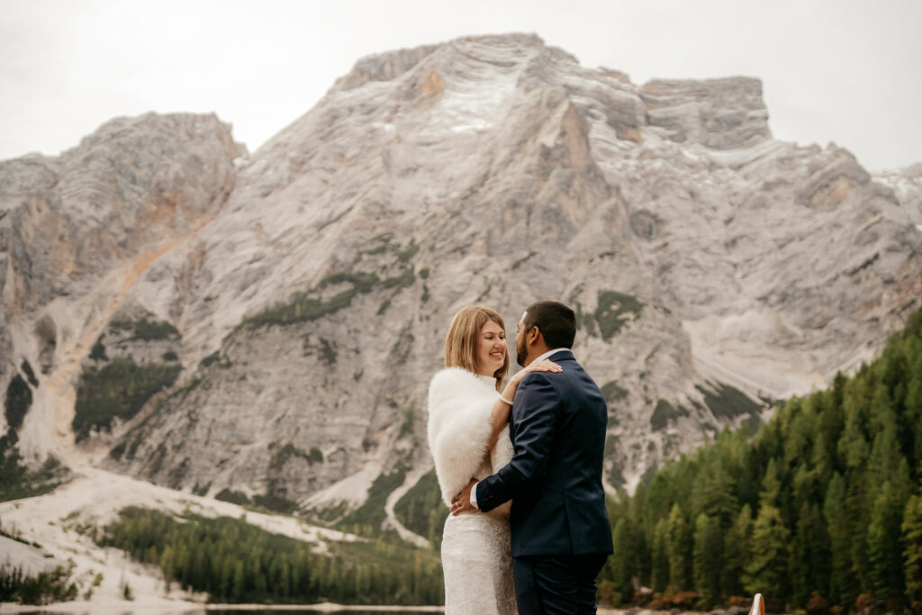 Couple embraces in front of majestic mountain landscape.