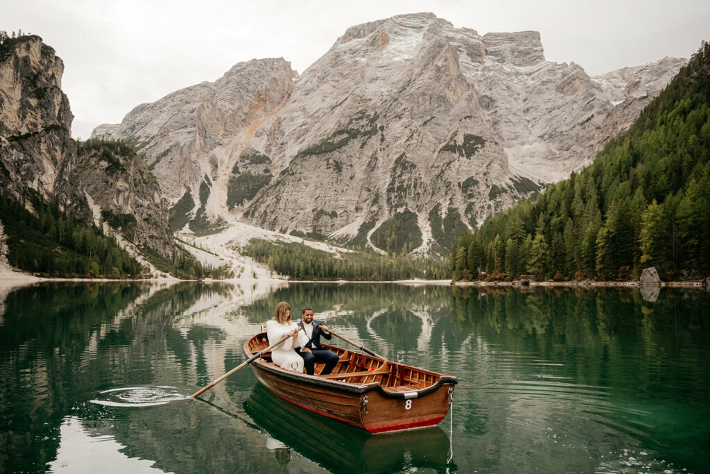 Couple rowing boat on mountain lake scenery.