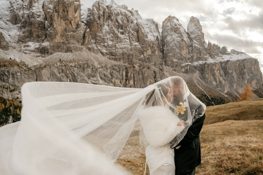 Bride and groom kissing with mountain backdrop.