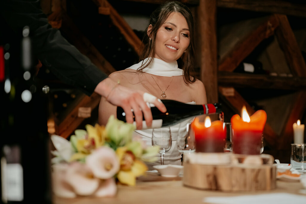 Woman at candlelit dinner with wine being poured.