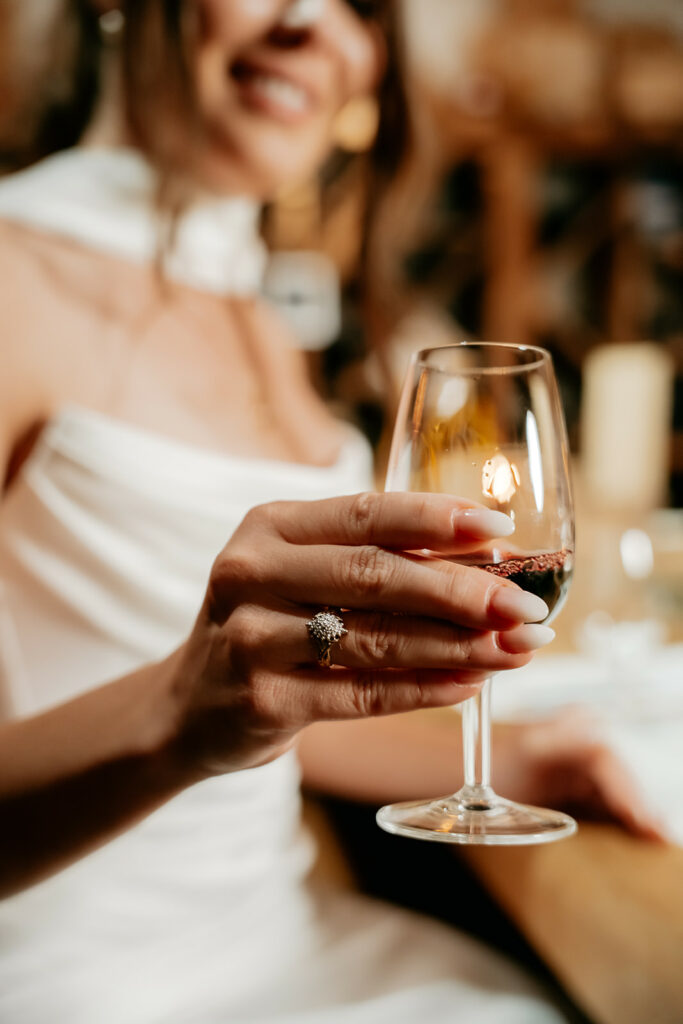 Woman holding wine glass, wearing elegant ring.