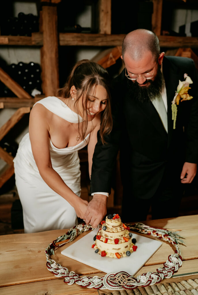 Couple cutting wedding cake together.