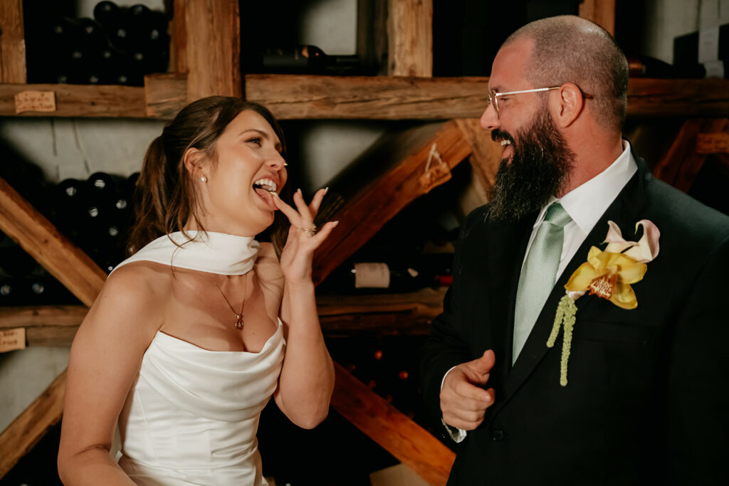 Happy couple laughing at wedding reception in wine cellar.