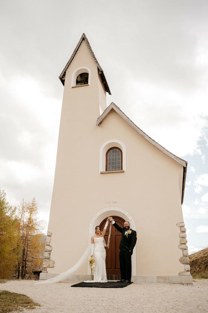 Bride and groom outside small chapel.