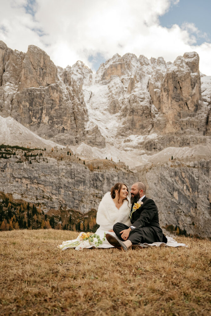 Couple in wedding attire by snowy mountain landscape.