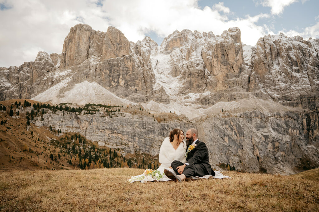 Couple sitting in front of large snowy mountains.