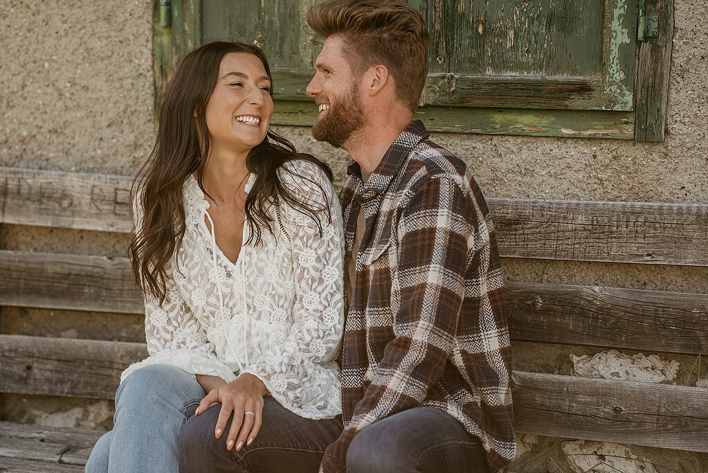 Smiling couple sitting on rustic wooden bench.