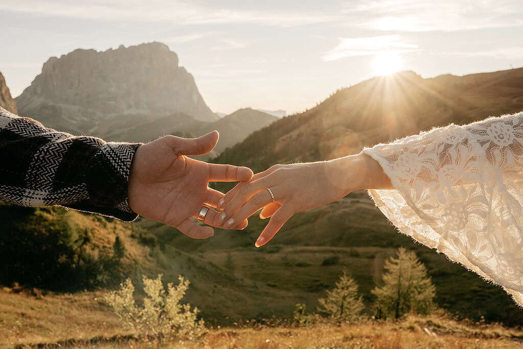 Couple holding hands at sunset in mountains.