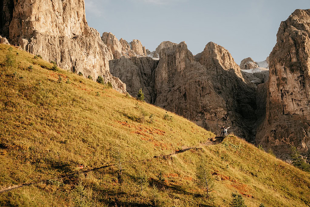 Hikers on a sunny mountain trail amidst cliffs