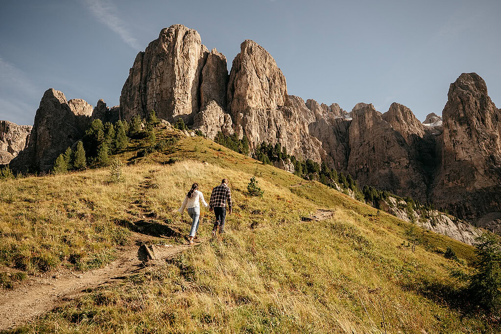 Couple hiking towards towering mountain landscape.