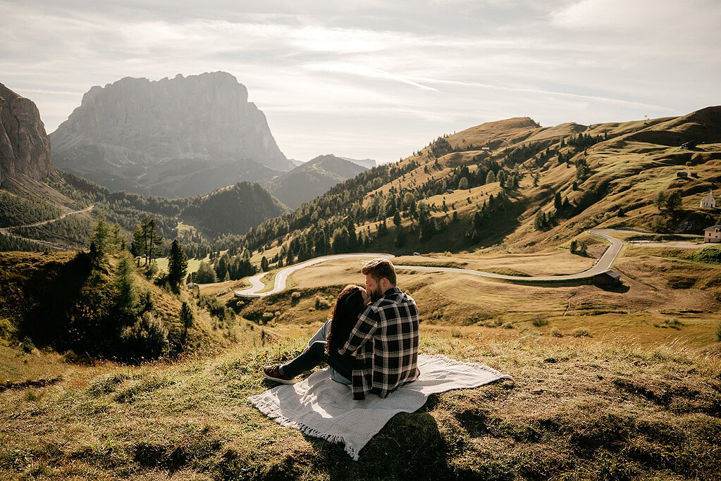 Couple enjoys scenic mountain view on picnic blanket.