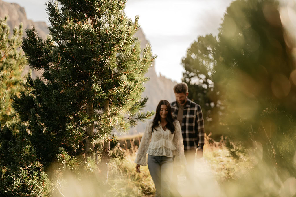 Couple walking through forest, sunlight filtering through trees.