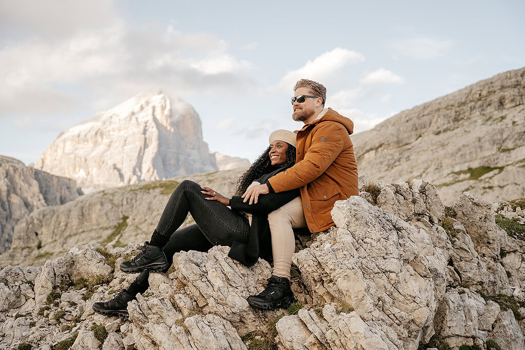 Couple sitting on rocky mountain landscape.
