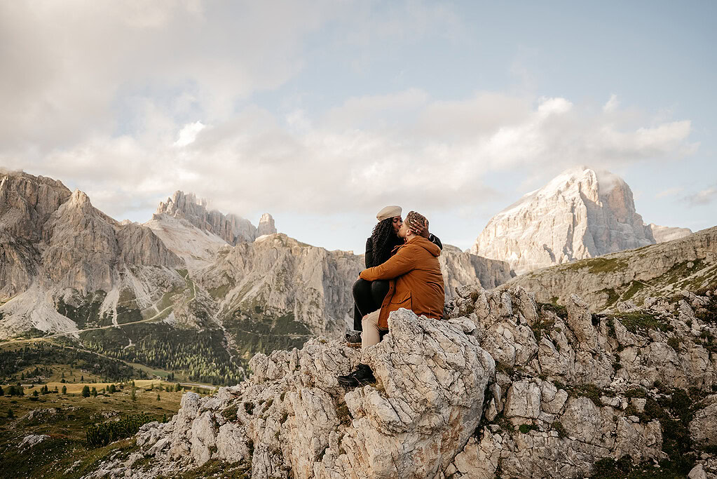 Couple sitting on rocky mountain with scenic view.