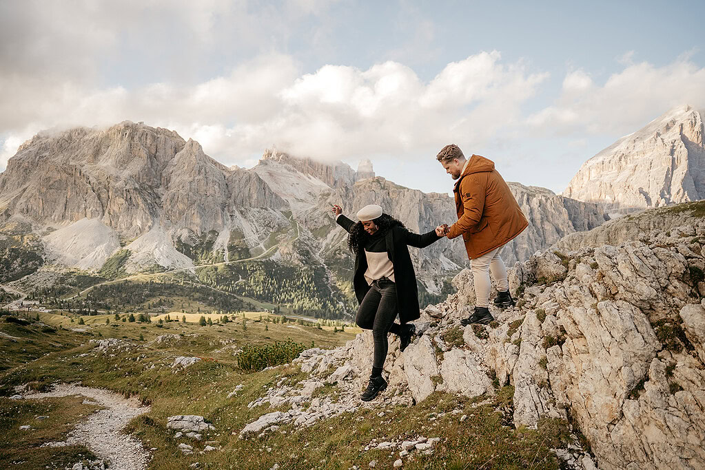 Couple hiking in scenic mountain landscape, holding hands.