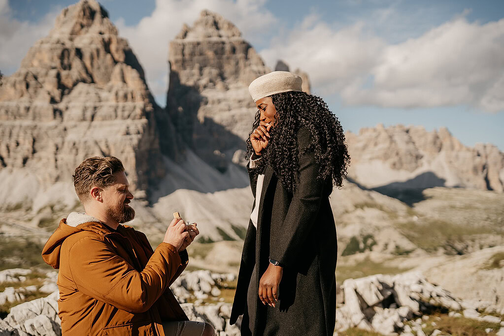 Man proposing to woman in mountainous landscape.