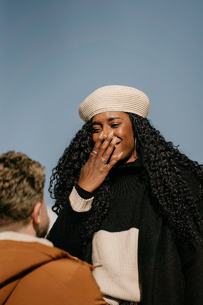 Woman smiling with a hat under blue sky.