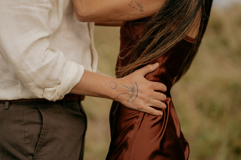 Close embrace showing tattooed arm on silk fabric.