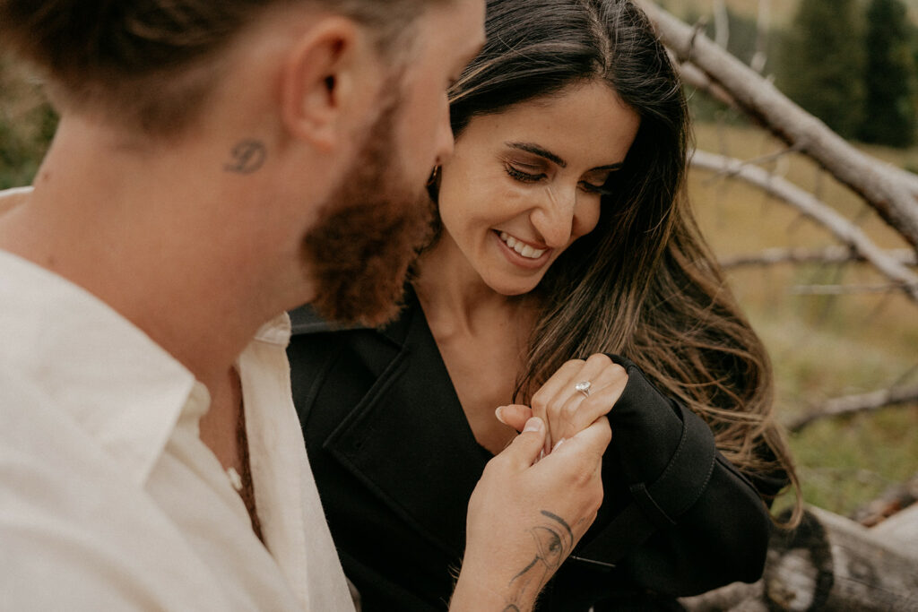 Couple smiling, showing engagement ring.
