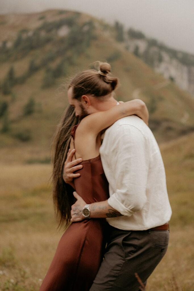 Couple embraces in scenic mountain landscape.