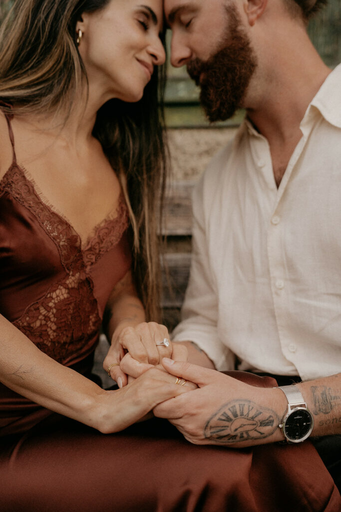 Couple holding hands, showing engagement ring.