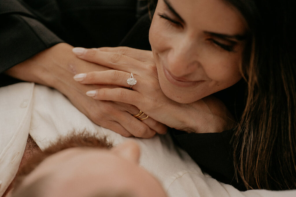 Woman smiling with engagement ring on hand.