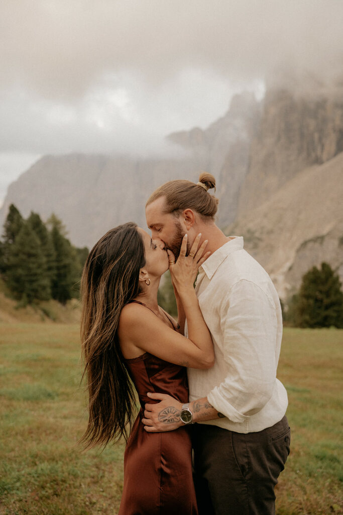 Couple kissing in scenic mountain landscape.