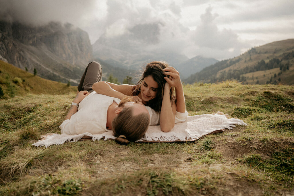 Couple relaxing on a blanket in mountains.