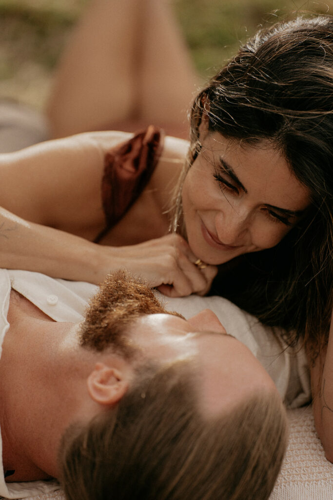 Couple laying and smiling at each other happily.