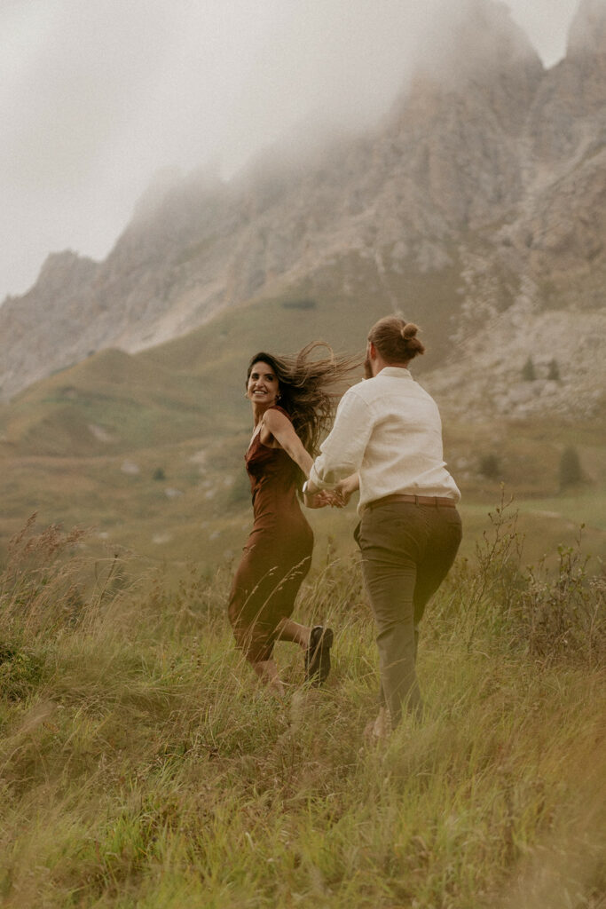 Couple holding hands, running in mountain landscape