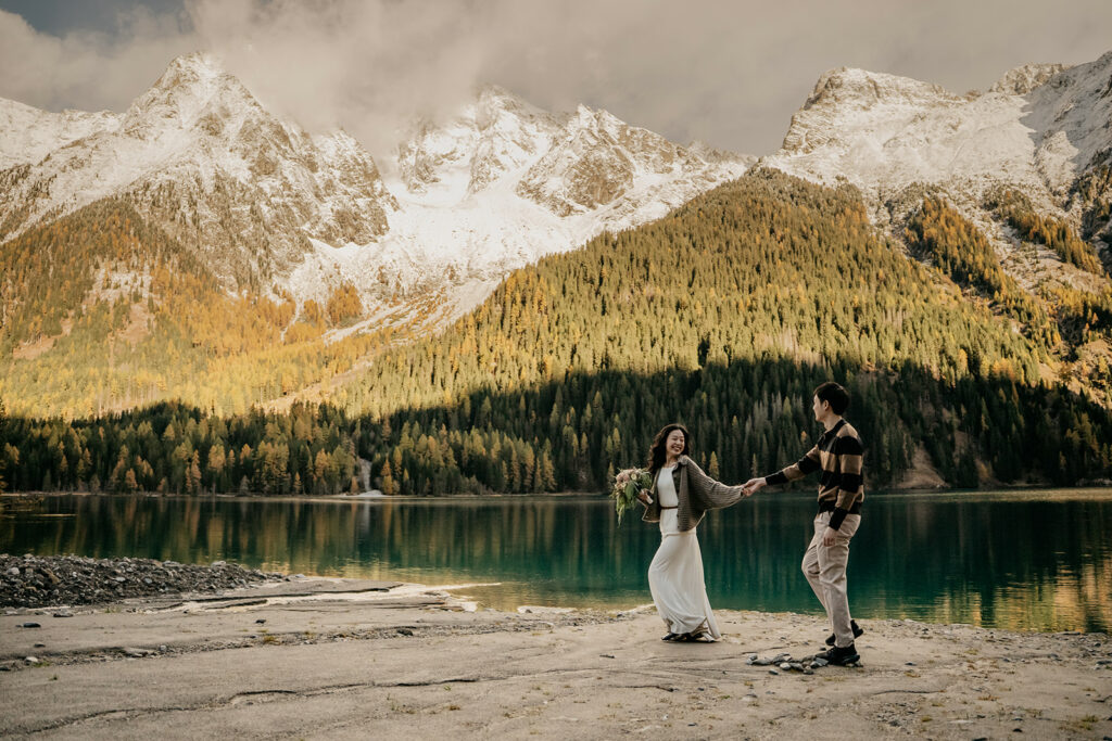 Couple holding hands, mountain background, scenic lake view.