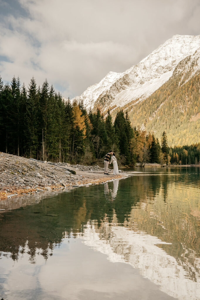 Couple kissing by snowy mountain lake