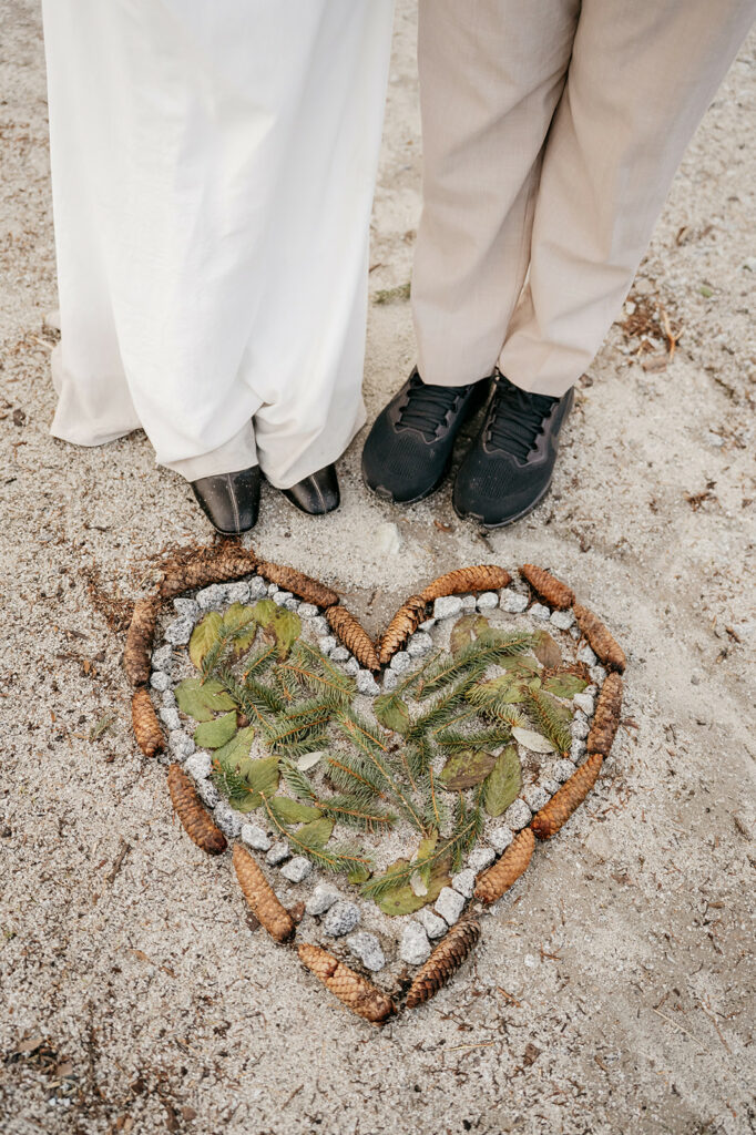 Two people standing by heart made of pine cones.