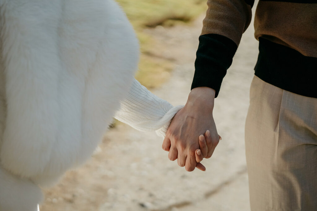 Couple holding hands outdoors in winter clothing.
