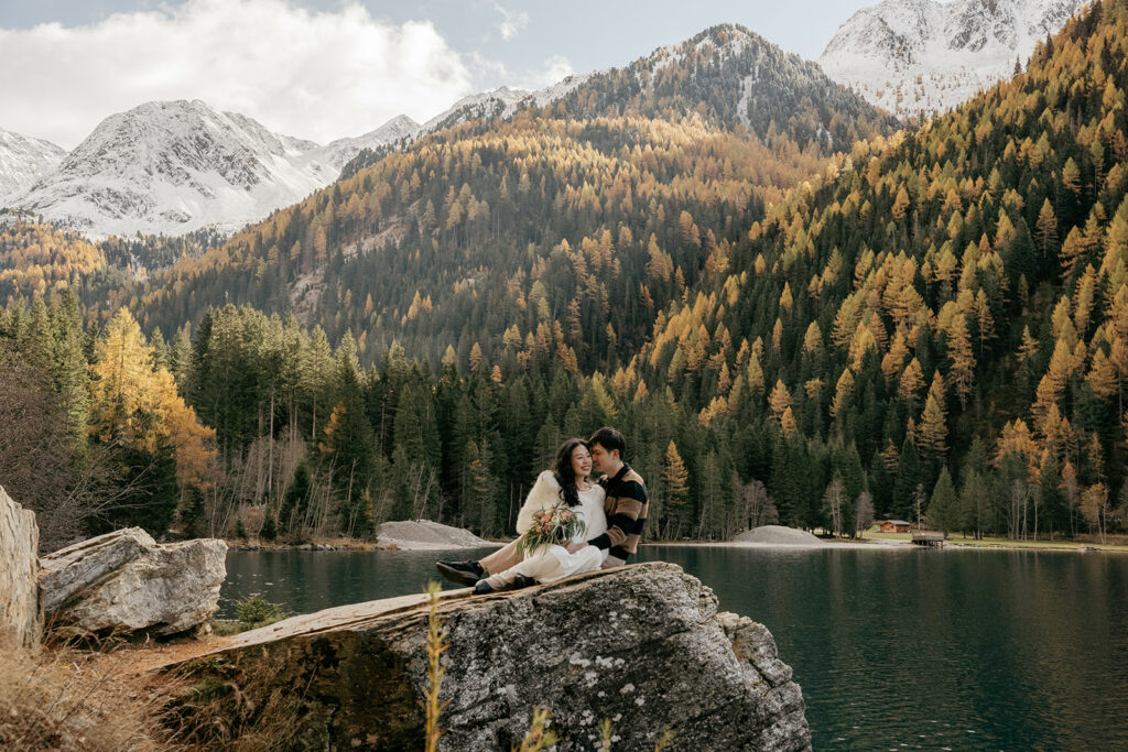 Couple embracing by scenic mountain lake in autumn.