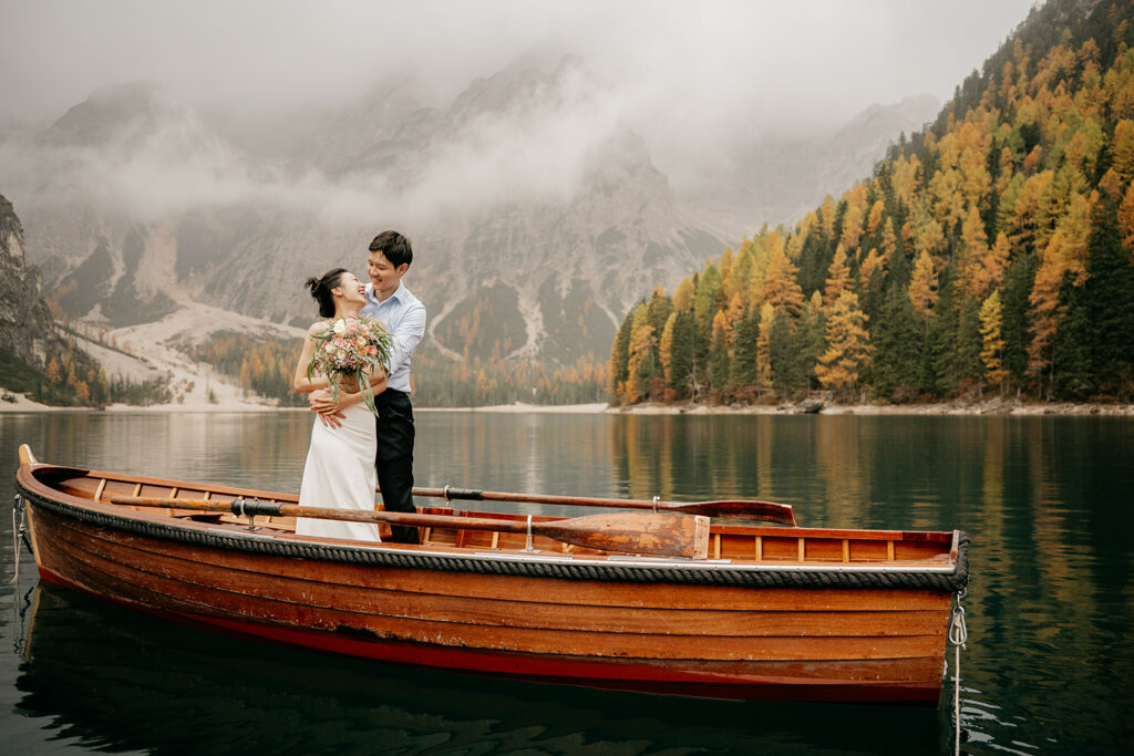 Couple embraces on boat in scenic mountain lake.