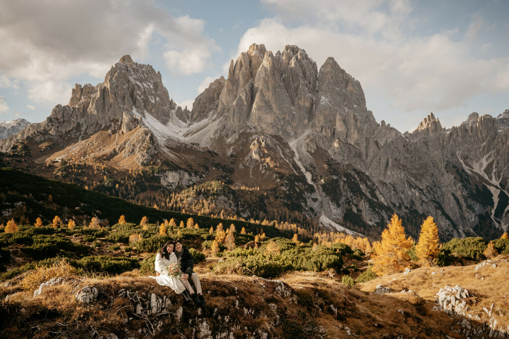 Couple sitting in front of scenic mountain landscape.