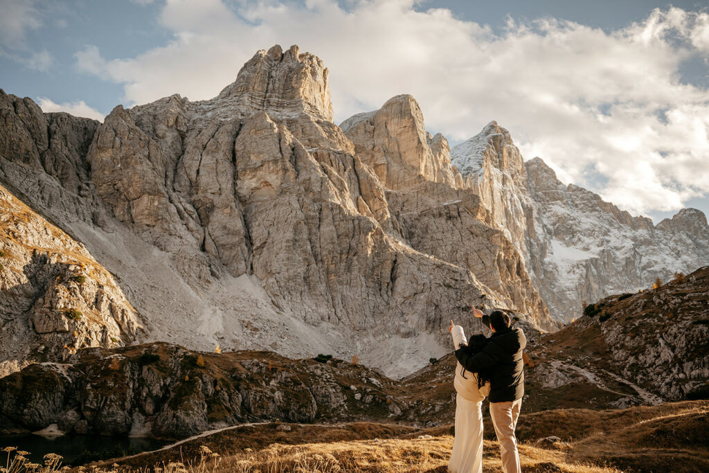 Couple admiring majestic mountain landscape at sunset.