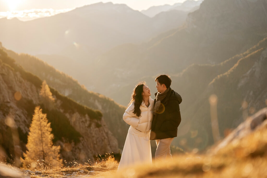 Couple smiling in sunny mountain landscape.