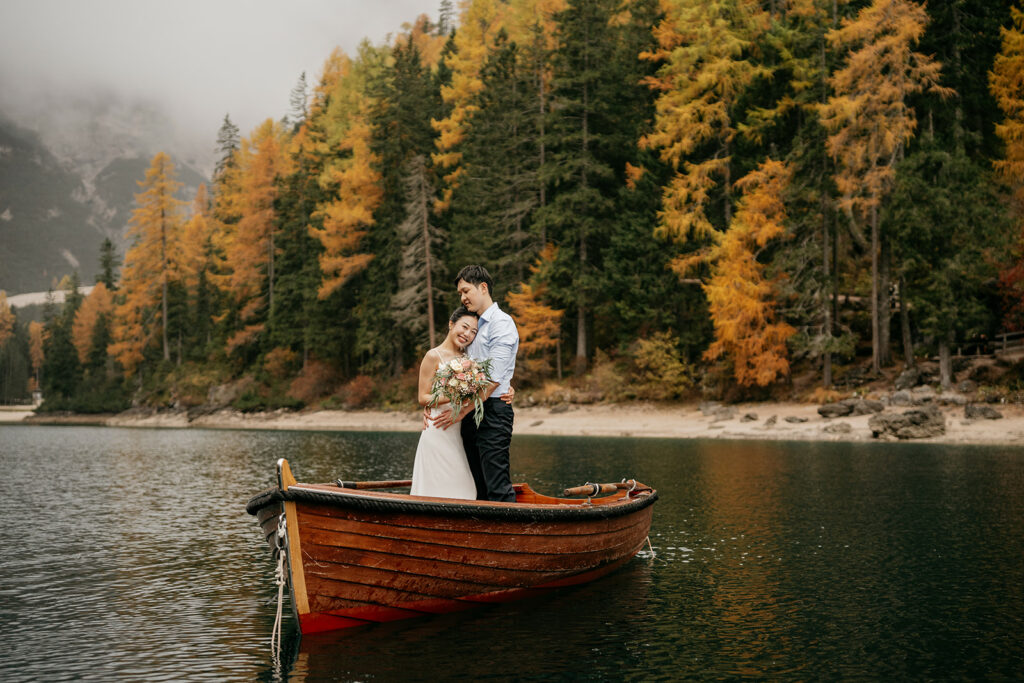 Couple embracing on boat, autumn forest backdrop