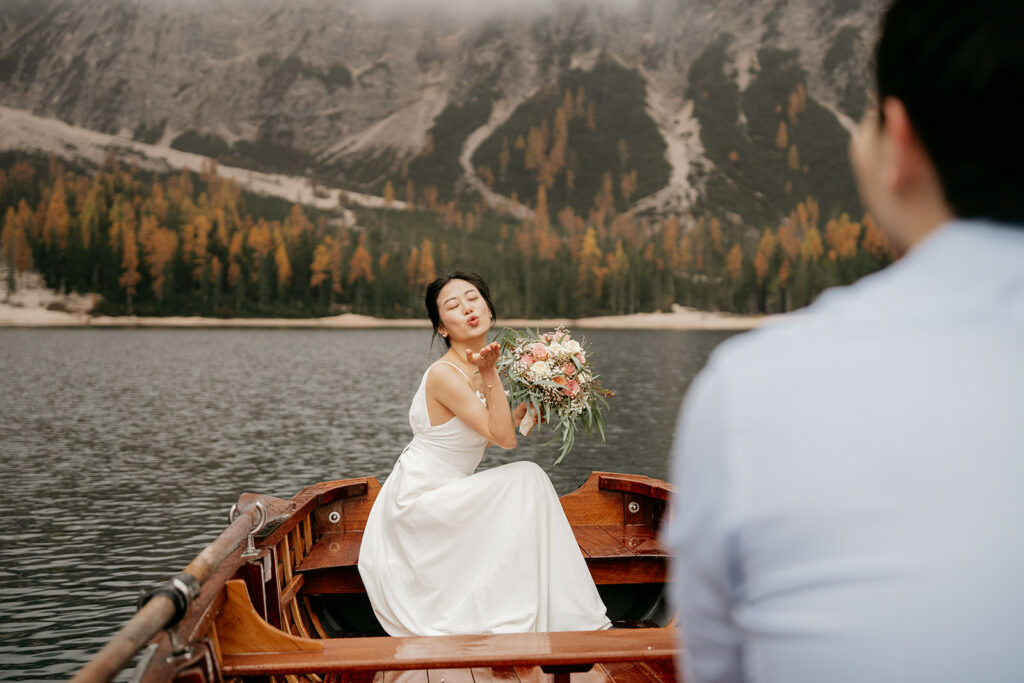 Bride blowing kiss on lake boat